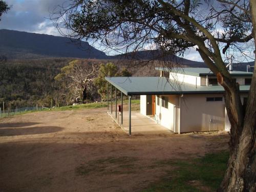 a white building with a blue roof next to a field at Hawksview at Mafeking in Mafeking