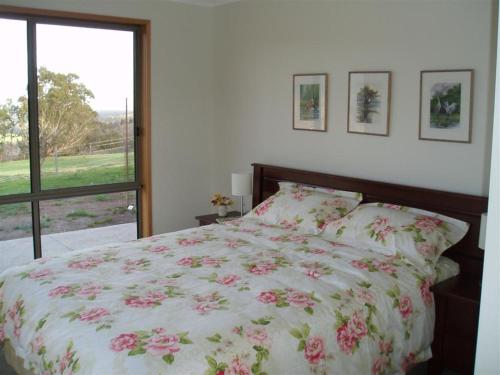 a bedroom with a bed with a floral bedspread and a window at Hawksview at Mafeking in Mafeking