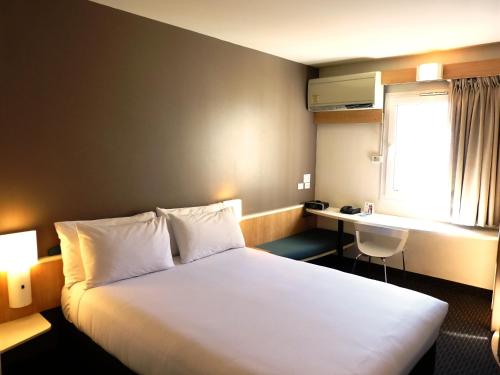 a hotel room with a bed and a desk at ibis Thornleigh in Thornleigh