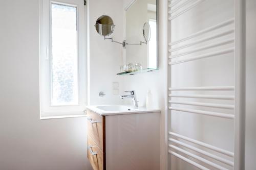 ein weißes Bad mit einem Waschbecken und einem Fenster in der Unterkunft Insulaner Apartments in Helgoland