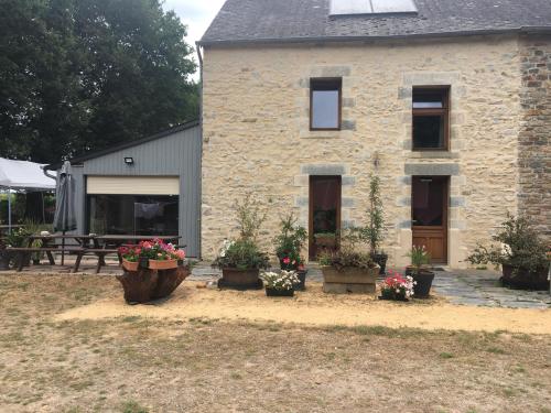 a stone house with potted plants in front of it at Le Clos Doré Parc in Bains-sur-Oust