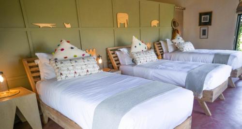 a bedroom with three beds with pillows on them at Ololo Safari Lodge & Farm in Nairobi