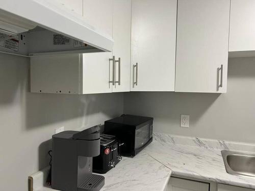 uma cozinha com armários brancos e um micro-ondas preto em Cozy Modern and Lavish 3 Bedroom Basement Suite em Winnipeg