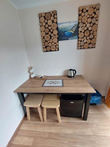a wooden table with two chairs and logs on the wall at Hostel & Apartments u Florka 2 in Zakopane