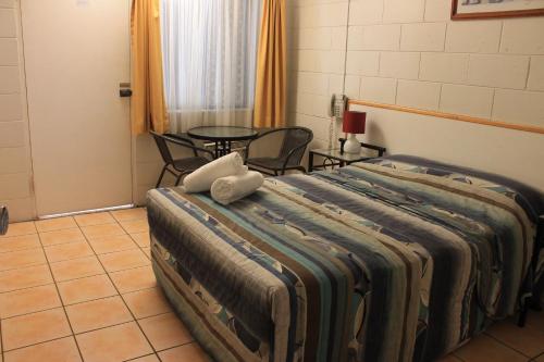 a large bed in a room with a table at Oasis Inn Apartments in Cairns