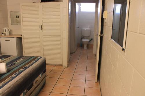 a room with a bathroom with a toilet and a bedroom at Oasis Inn Apartments in Cairns