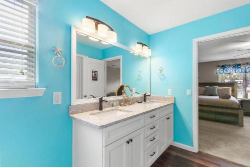 een blauwe badkamer met een wastafel en een spiegel bij Cruz Family Treasure All In One Home in Navarre