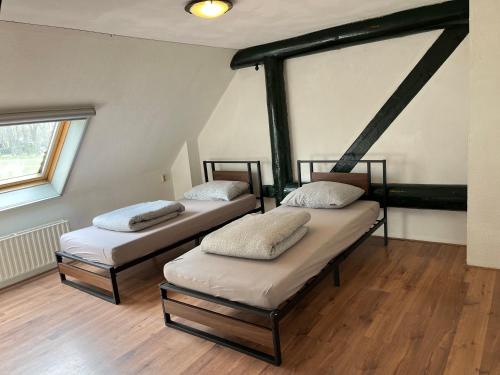 two beds in a room with wooden floors and a window at Familiehuis voor 13 personen in Diever