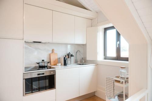 een witte keuken met witte kasten en een raam bij Novo Apartamento Porto - Vistas Rio Douro in Porto