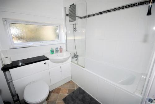 a white bathroom with a toilet and a sink at Get Away Holiday Home With Hot Tub Sleeps 6 in Peacehaven
