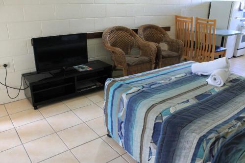 a room with a bed and a flat screen tv at Oasis Inn Apartments in Cairns