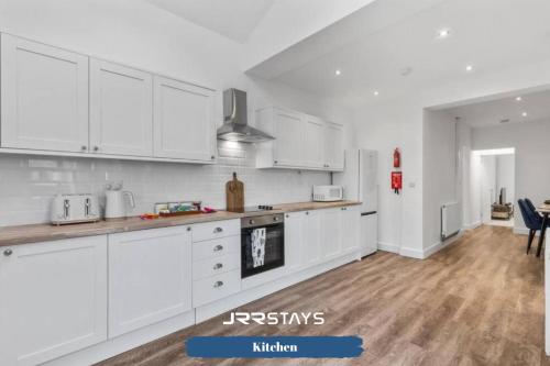 a kitchen with white cabinets and a wooden floor at Burton on Trent - 3 Bedroom, Sleep 7, Wi-Fi - JRR Stays in Burton upon Trent