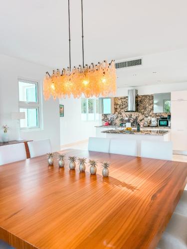 a dining room with a wooden table and a kitchen at Peninsula Esmeralda Luxury Villas in San Felipe de Puerto Plata