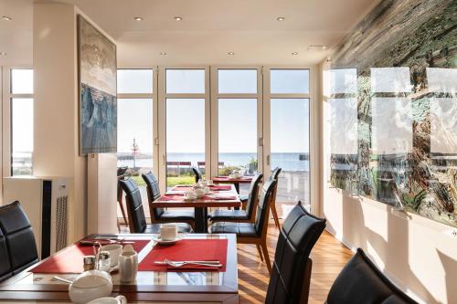 a restaurant with tables and chairs with a view of the ocean at Hotel Rickmers' Insulaner in Helgoland