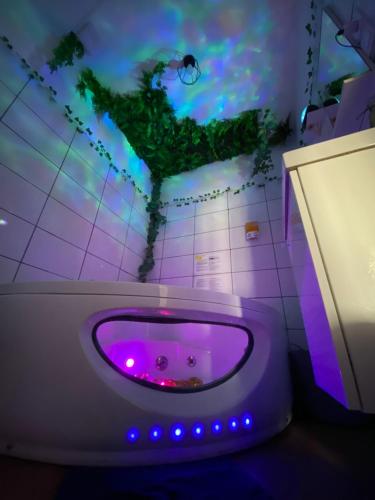 Le monde D avatar avec Balneo et table de massage في لابريسل: مرحاض أرجواني في حمام مع أضواء أرجوانية