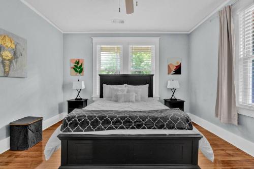 a bedroom with a large bed and two windows at Cheerful Midtown home with view of Rhodes College in Memphis