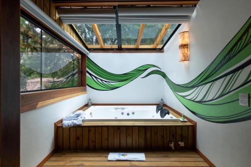 a bathroom with a bath tub with a window at Pousada Canto da Nascente in Monte Verde