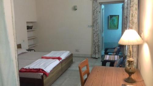 a bedroom with a bed and a table with a lamp at "Nain's Kunj" A Traveller's Home in Jodhpur