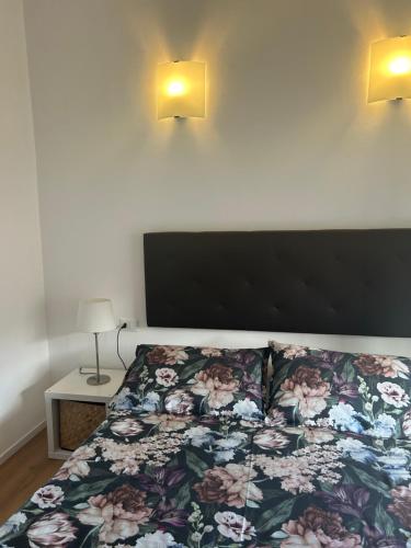 a bedroom with a bed with a floral bedspread and two lights at Civico 28 in Pescara