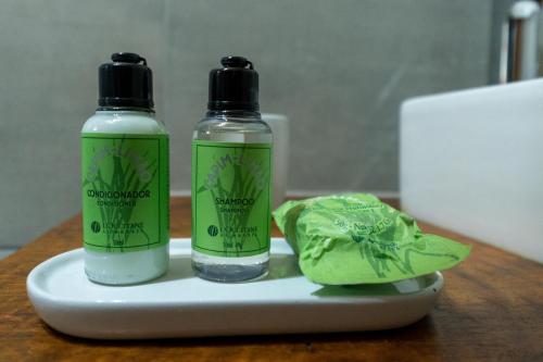 two bottles of soap sitting on a plate with a green leaf at Pousada Canto da Nascente in Monte Verde