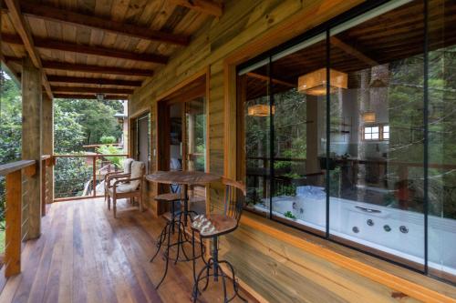 a screened in porch with glass windows and a bar at Pousada Canto da Nascente in Monte Verde