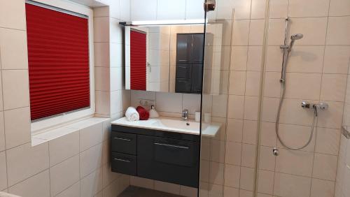 ein Badezimmer mit einem Waschbecken und einer Dusche mit roten Jalousien in der Unterkunft Ferienwohnung Goldnugget in Schwarzach im Pongau