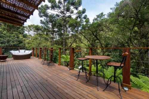 a deck with a tub and chairs and a table at Pousada Canto da Nascente in Monte Verde