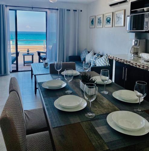 a dining room with a table with plates and wine glasses at Cancun Hotel Zone, Beachfront 2 BR Apartment - Prime Location in Cancún
