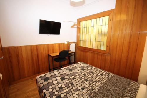 a bedroom with a bed and a desk and a television at Nuevo Balmes Habitaciones in Barcelona