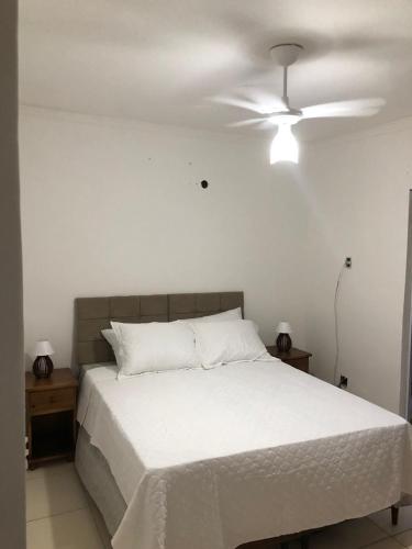 a bedroom with a white bed with a ceiling fan at Pousada Litorânea in Saquarema