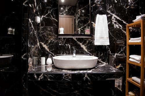 a bathroom with a white sink and black marble walls at Stylish Apartment, Acropolis view in Athens