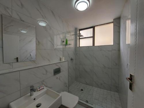a white bathroom with a sink and a mirror at Umhlanga Beach 3 Bedroom Apartment in Durban