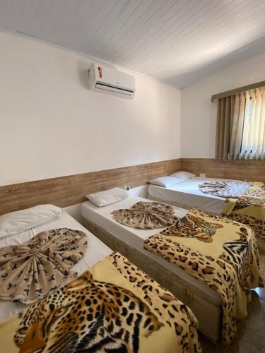 a room with four beds with leopard print sheets at Aparecida Akuto's Pousada in Aparecida