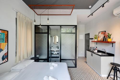 a bedroom with a white bed and a bathroom at Levinski Market Hotel in Tel Aviv