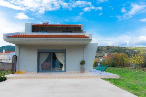 a small white house with two chairs in front of it at Stellas guesthouse near Arachova in Stírion