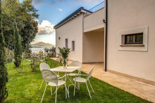 a patio with a table and chairs on the grass at Vigna Caio Relais & Spa in Bracciano