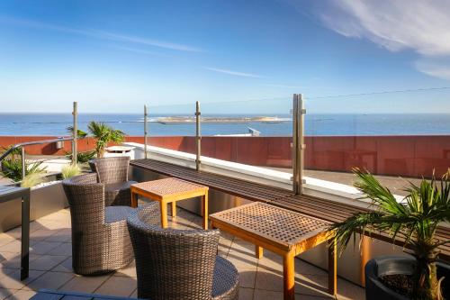 einen Balkon mit Tischen, Stühlen und Meerblick in der Unterkunft Hotel auf den Hummerklippen in Helgoland