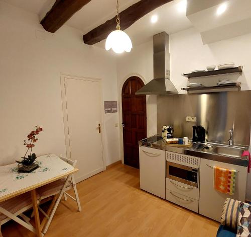 cocina con fogones, fregadero y mesa en Apartaments Mare Nostrum, en Sitges