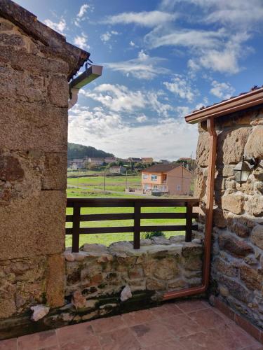 a stone building with a view of a field from a window at Casa do Boedo in Camariñas