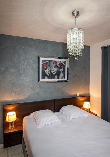 une chambre avec un grand lit blanc avec un lustre dans l'établissement Le Jardin de Babylone 