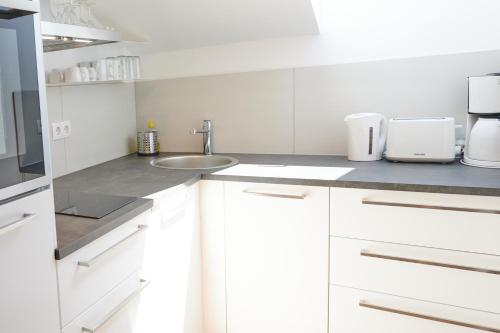 a kitchen with white cabinets and a sink at Apartments at Winterhafen in Linz