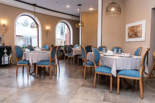 a dining room with tables and blue chairs at Hotel Royal in Urziceni