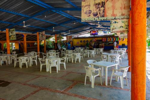 um restaurante com mesas brancas e cadeiras brancas em Balneario y Cabañas ISIS em La Huerta