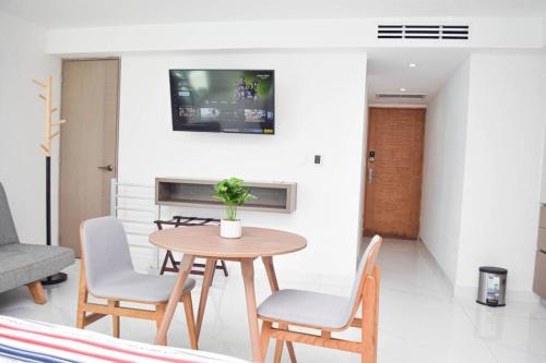 a table and chairs in a living room with a tv at Hermoso estudio frente al mar, balcon, gym 3504 in Cancún