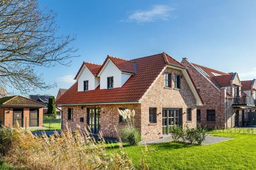 a large brick house with a red roof at Ferienhaus Maira, mit Garten und Sauna in Greetsiel