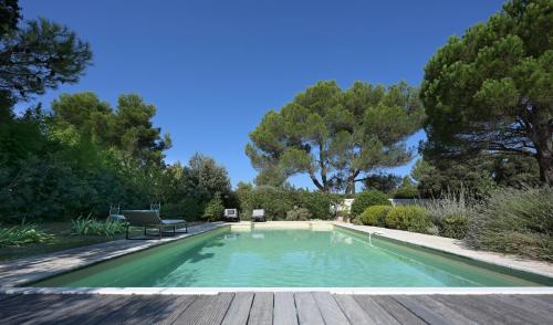 una piscina en un jardín con terraza de madera en Maison Les Chênes, en Eygalières