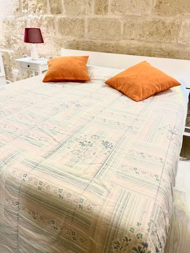 una cama con almohadas naranjas encima en Principe Amedeo, en Trani