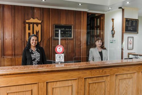 two women are standing behind the counter of a courtroom at Hotel Melillanca in Valdivia