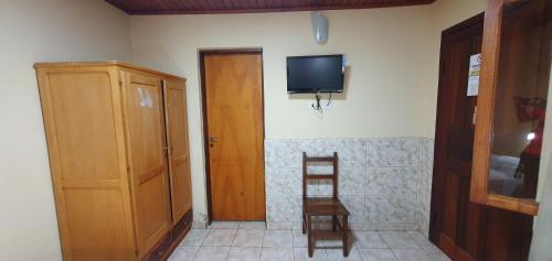 um quarto com uma televisão, uma cadeira e uma porta em Hospedaje Jose Gorgues em Puerto Iguazú