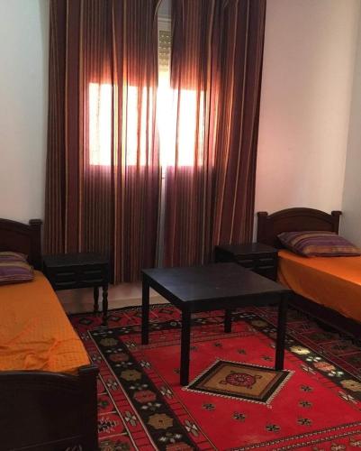 una camera con due letti e un tavolo e una finestra di Vacances à petit prix Lot Shems a Safi